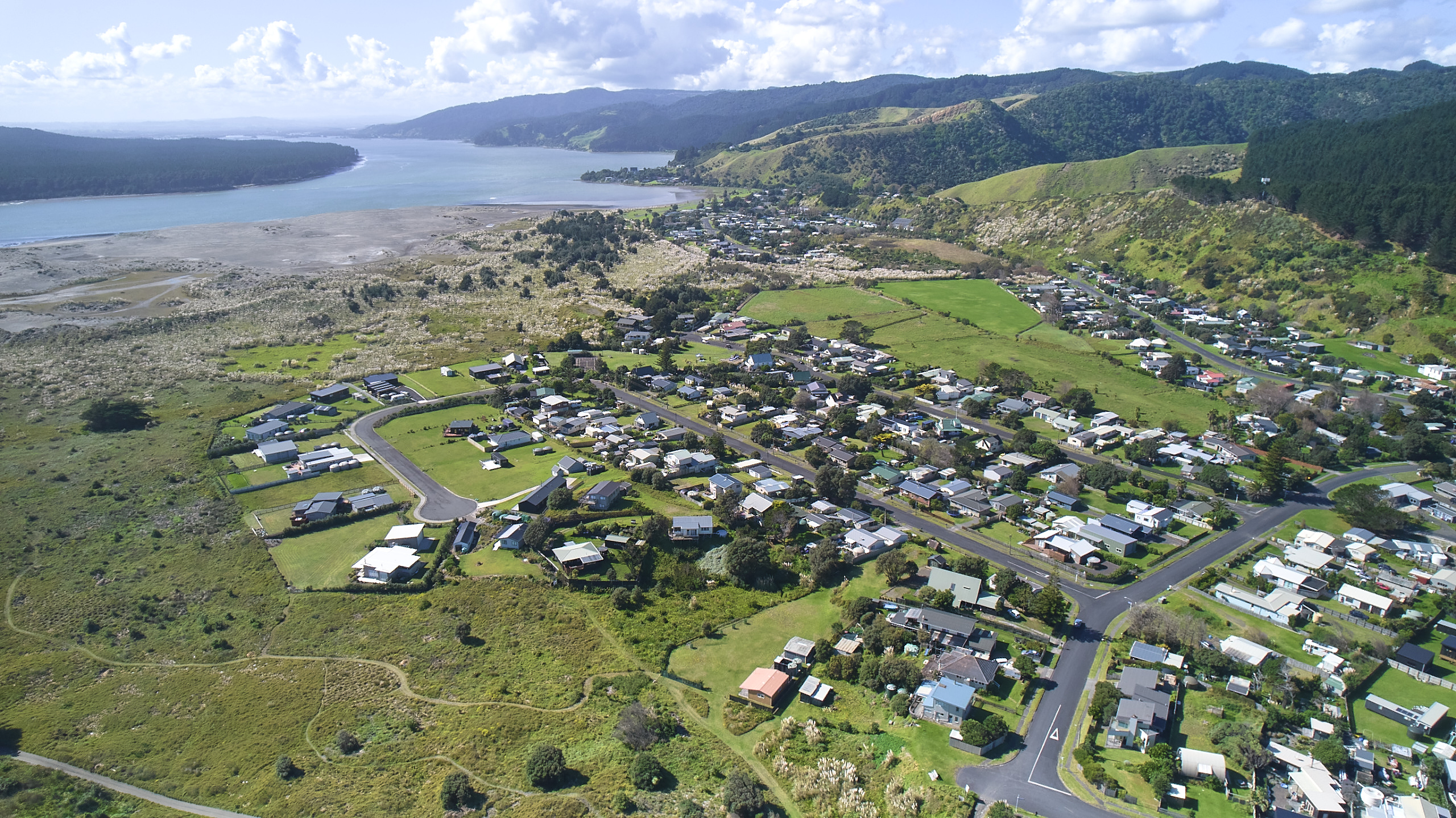 View overlooking houses surrounded by green hills and a river in the distance.