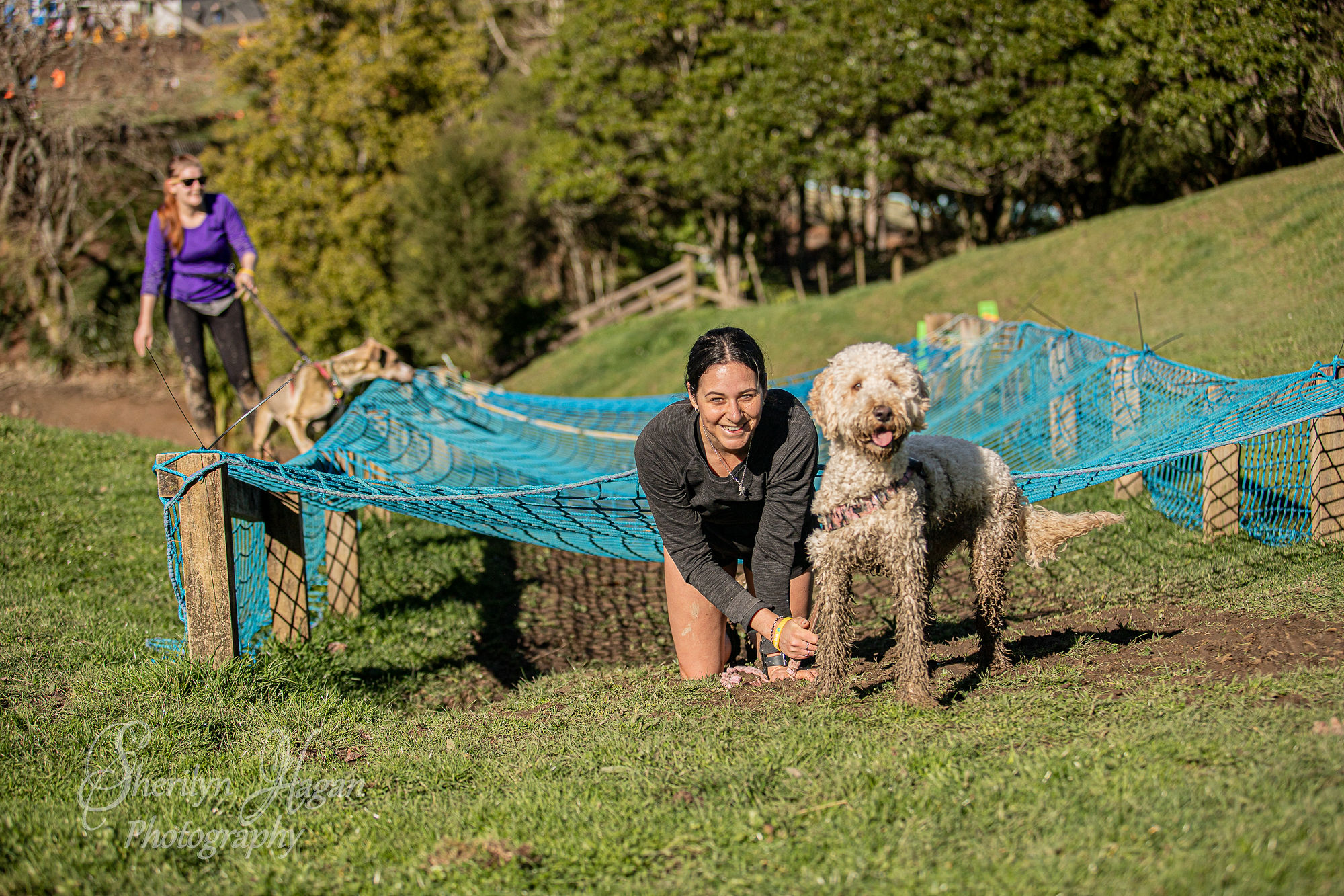 Woman and muddy dog in front of netting