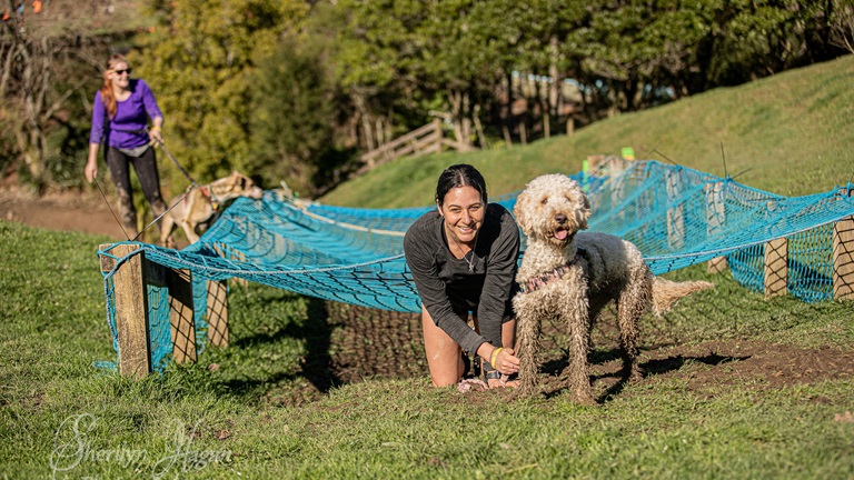 Woman and muddy dog in front of netting