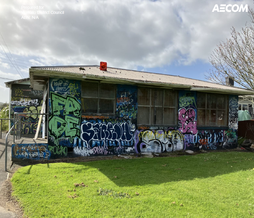 A small building with graffiti-covered walls stands under a cloudy sky. The vibrant graffiti features various colors and tags, creating a lively urban atmosphere.