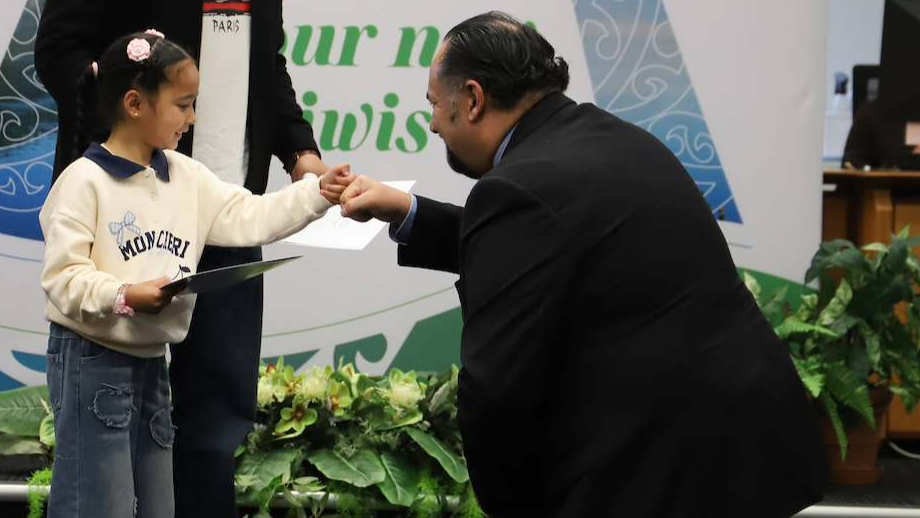 Child receives a certificate and greets the Mayor during an citizenship ceremony.