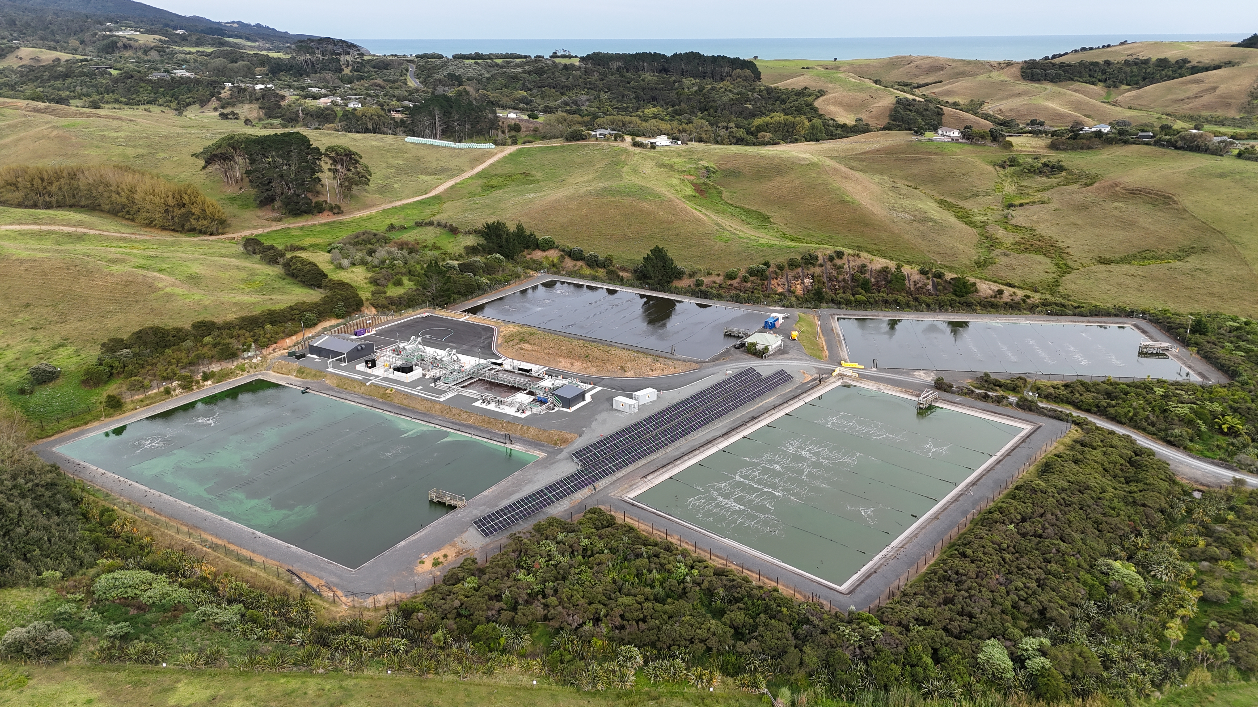 Aerial view of wastewater treatment plant with four treatment ponds and solar panels in the center