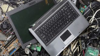 A pile of e-waste featuring two old laptops with tangled cables and circuit boards, conveying a sense of clutter and technological obsolescence.